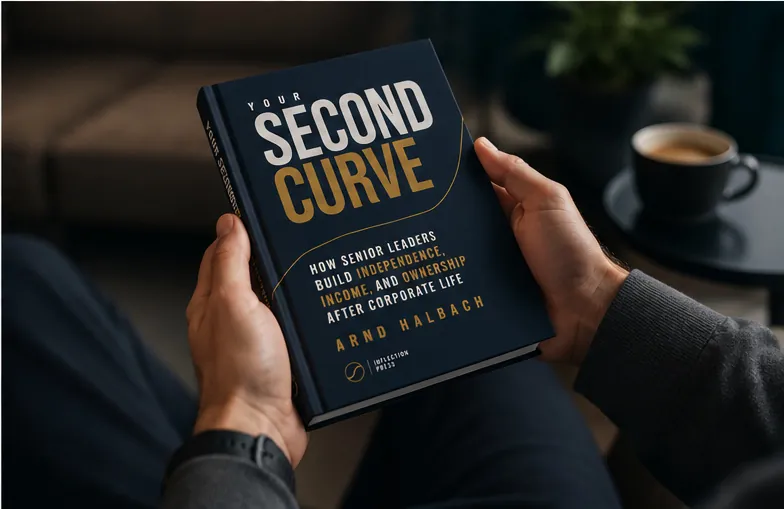 Overhead view of a reader holding the closed Your Second Curve hardcover in both hands, a cup of coffee on the side table beside them.